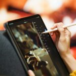 Creating digital art on a tablet with a stylus, cozy by the fireplace.